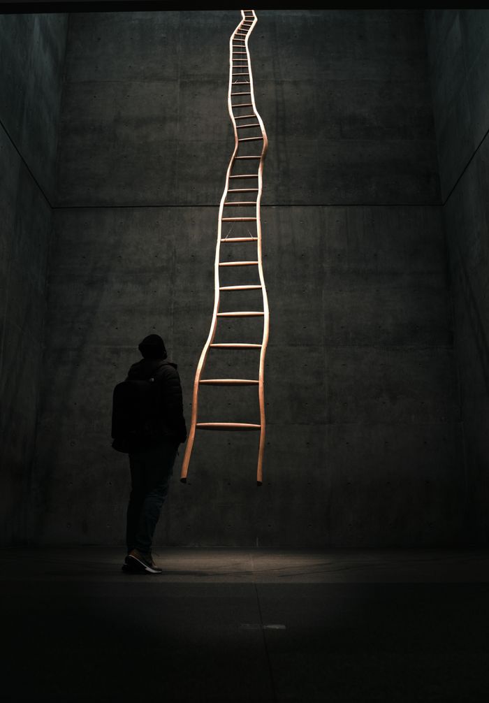 Mastering the First Impression: Your intriguing post title goes here A lone figure gazes at a surreal ladder reaching upwards in a dimly lit urban setting.